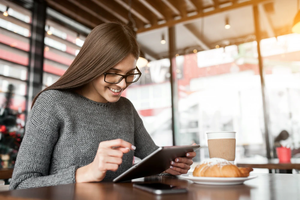 Woman reading an online blog sitting in a cafeteria